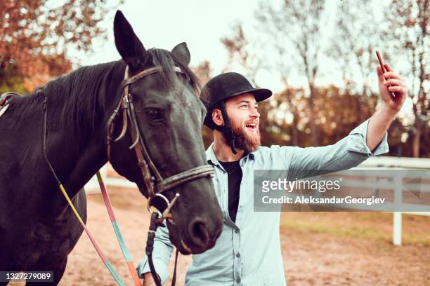 lächelnde männliche selfie mit schönen schwarzen pferd auf ranch - horse and male and riding stock-fotos und bilder