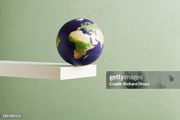 a world globe balanced on the edge of a shelf - desktop globe stock-fotos und bilder