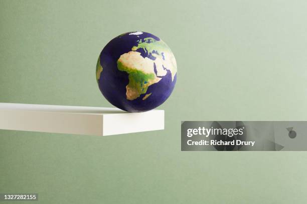 a world globe balanced on the edge of a shelf - risque photos et images de collection