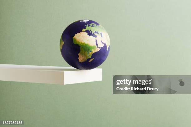 a world globe balanced on the edge of a shelf - environmental issues stock pictures, royalty-free photos & images