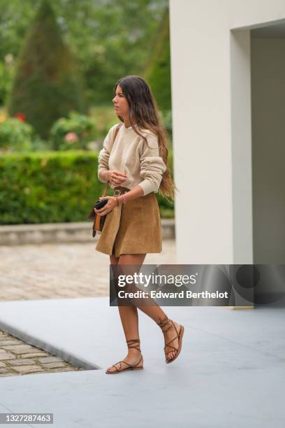 Guest wears a beige wool pullover, a brown suede short wrap belted skirt, brown shiny leather laces sandals / shoes, brown LV monogram in coated...