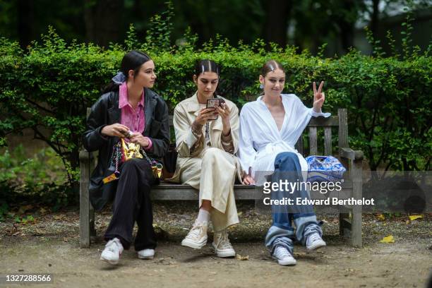 Guest wears a blue tulle headband, a white ribbed velvet shirt, a black shiny leather jacket, a multicolored with rainbow reflect handbag, black...