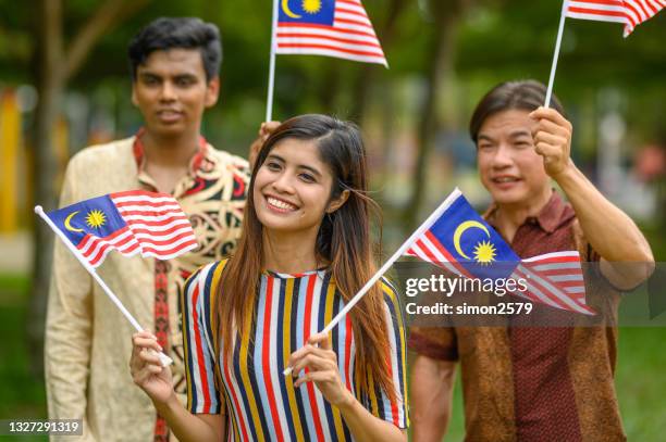 malaysian multi-ethnic group people waving with malaysian flag at public park - malaysia flag stock pictures, royalty-free photos & images