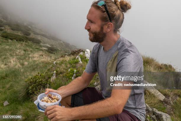 male hiker eats snack on mountain trail - picnic rug stockfoto's en -beelden
