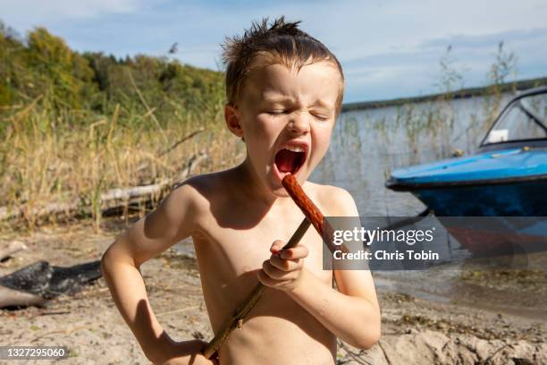 young boy with sausage on a stick pretends to be singing - alleen jongens stockfoto's en -beelden