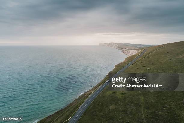 car driving along a road on the coastline photographed by drone, isle of wight, united kingdom - cross golf stockfoto's en -beelden