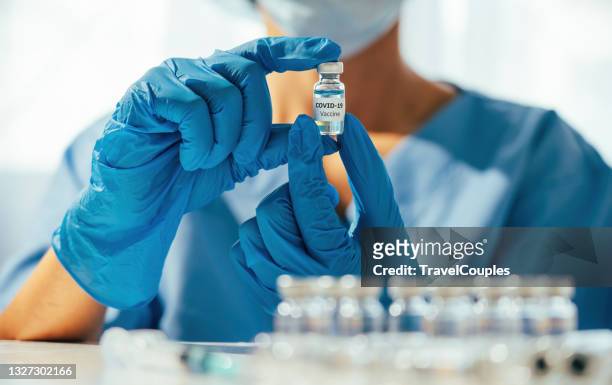 doctor hands in protective gloves holding coronavirus 2019-ncov vaccine vial. development and creation of a coronavirus vaccine covid-19. - coronavirus 2019 stock pictures, royalty-free photos & images