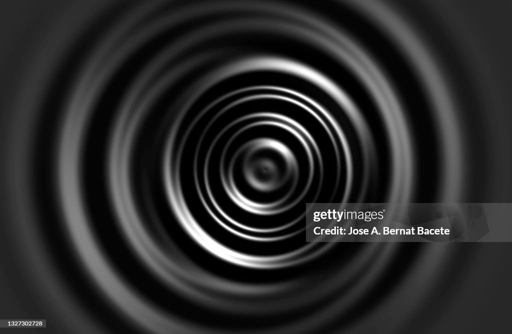 Full frame of concentric circles on a moving dark liquid surface.