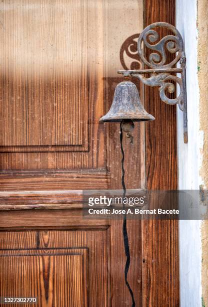 ancient door of wood in the street and a small metal bell with a chain. - alcudia stockfoto's en -beelden
