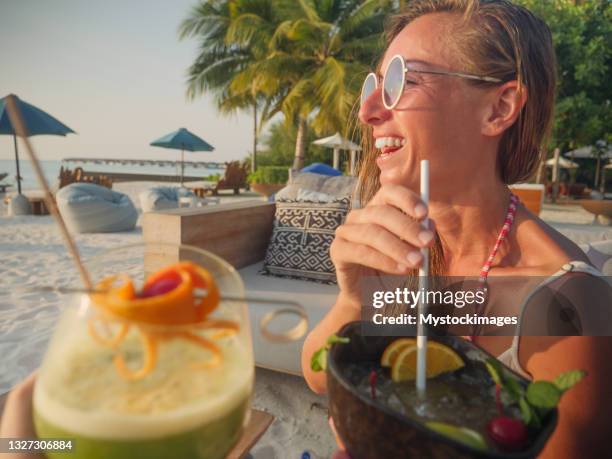 pov de couple prenant un cocktail au coucher du soleil sur la plage tropicale - bar de plage photos et images de collection