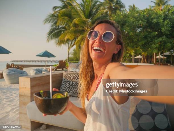 woman having cocktail at sunset on tropical beach and taking selfie - beach cocktail party stock pictures, royalty-free photos & images