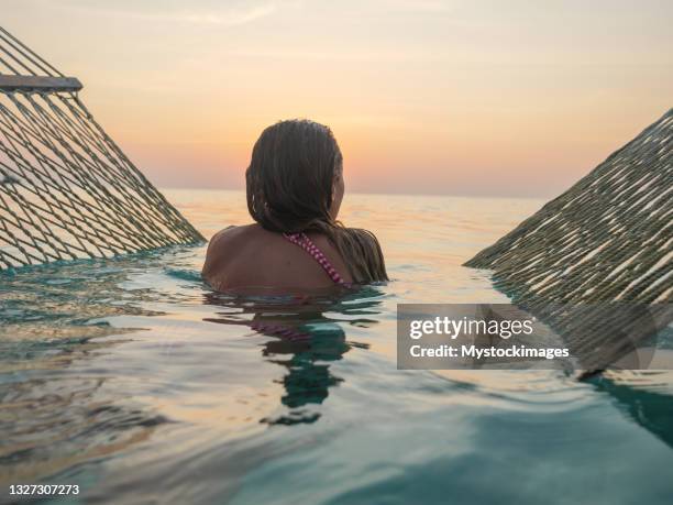 young woman watching sunset from sea hammock - zen like stock pictures, royalty-free photos & images