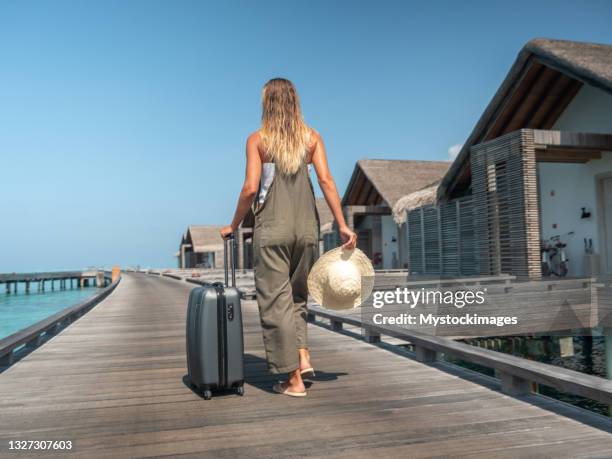 woman pulls trolley on wooden pier in tropical destination - blonde long legs 個照片及圖片檔
