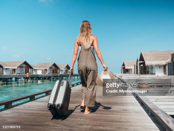 woman pulls trolley on wooden pier in tropical destination - carry on bag imagens e fotografias de stock