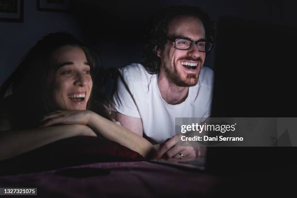 laughing married couple watching movie on laptop - laptop netbook fotografías e imágenes de stock