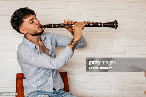 young man playing clarinet at home - klarinett bildbanksfoton och bilder