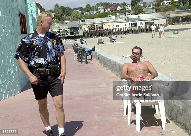 Sunbather checks out Capitola Police Officer Andrew Dally''s Hawaiian shirt uniform as he walks his beat July 16, 2001 in Capitola, CA. The Capitola...