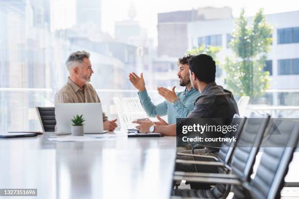 tres empresarios reunidos en una mesa de sala de juntas. - three people fotografías e imágenes de stock