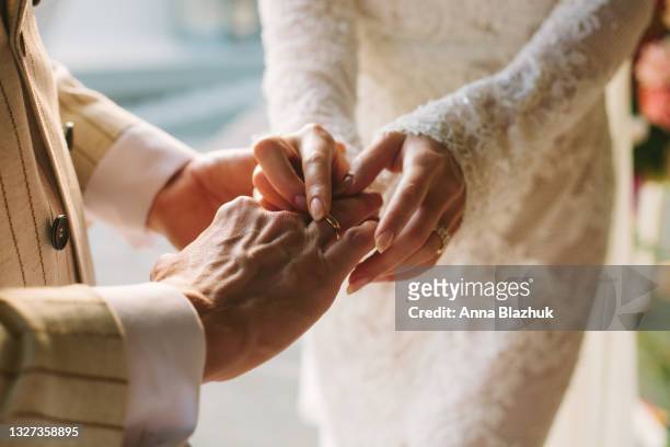 bride putting ring on groom's finger. rings exchange. happy couple celebrating wedding outdoors in summer. - cerimonia di nozze foto e immagini stock