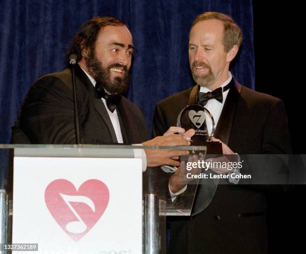 Italian operatic tenor Luciano Pavarotti receives a trophy from Michael Green at the 1998 MusiCares benefit dinner on February 23, 1998 in New York,...
