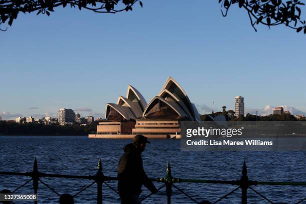 Man walks along the boardwalk at Milsons Point as the Opera House is seen across the harbour on July 07, 2021 in Sydney, Australia. Lockdown...