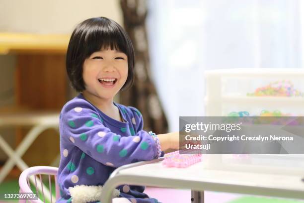 child laughing out loud with craft colorful rubber loom bands - ボブヘア ストックフォトと画像