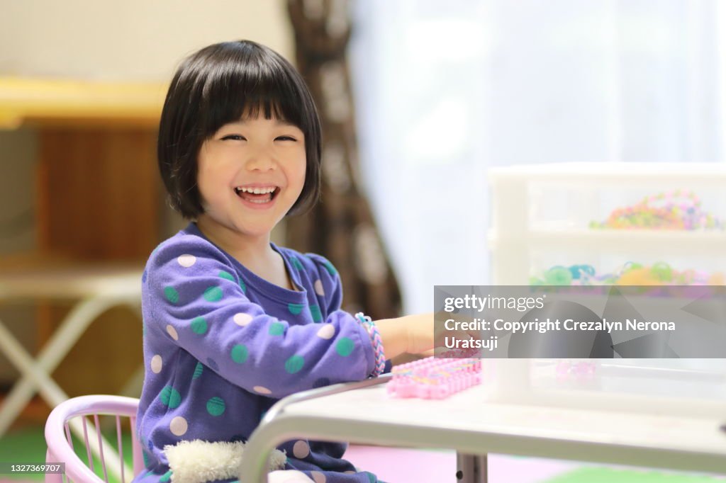 Child Laughing Out Loud with Craft Colorful Rubber Loom Bands