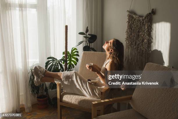 pretty woman drinking morning coffee at cozy sunlight apartment. - vida cotidiana fotografías e imágenes de stock