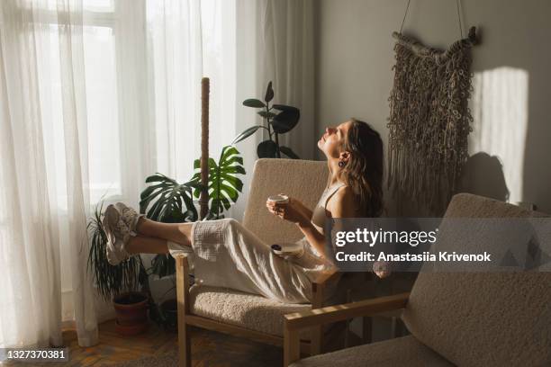 pretty woman drinking morning coffee at cozy sunlight apartment. - bank interior stockfoto's en -beelden