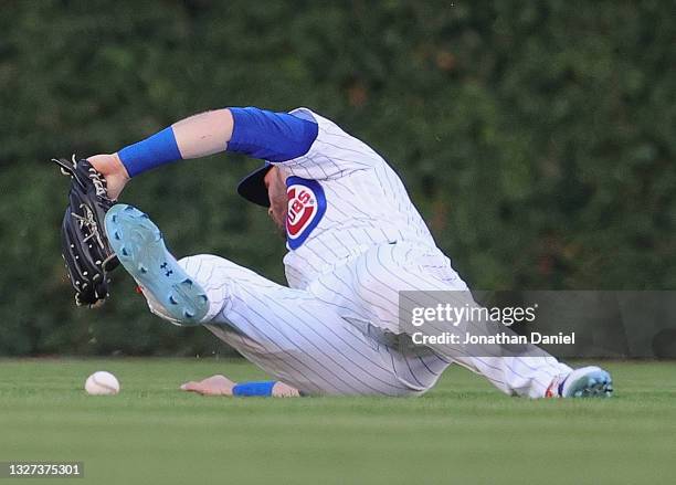 Ian Happ of the Chicago Cubs drops a ball hit by Rhys Hoskins of the Philadelphia Phillies in the 2nd inning, allowing runs to score at Wrigley Field...