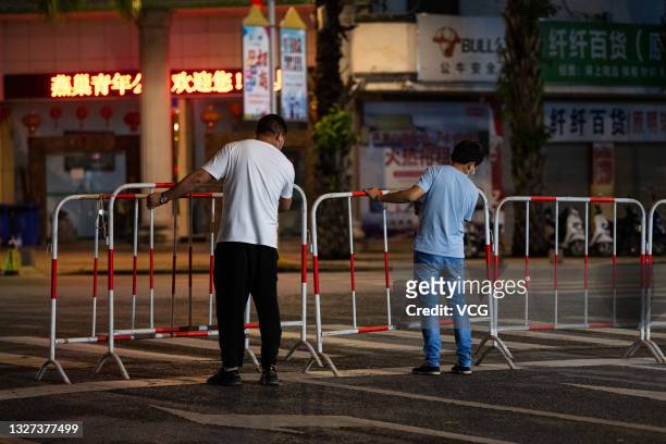 Staff members set up barricade on the street after the emergence of new COVID-19 cases on July 7, 2021 in Ruili, Yunnan Province of China.