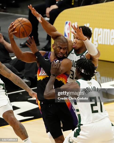 Chris Paul of the Phoenix Suns is pressured by Giannis Antetokounmpo and Jrue Holiday of the Milwaukee Bucks during the second half in Game One of...