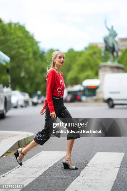 Leonie Hanne wears gold Chanel earrings, a gold Chanel large chain pendant necklace, a red wool pullover with embroidered white pearls to sign...