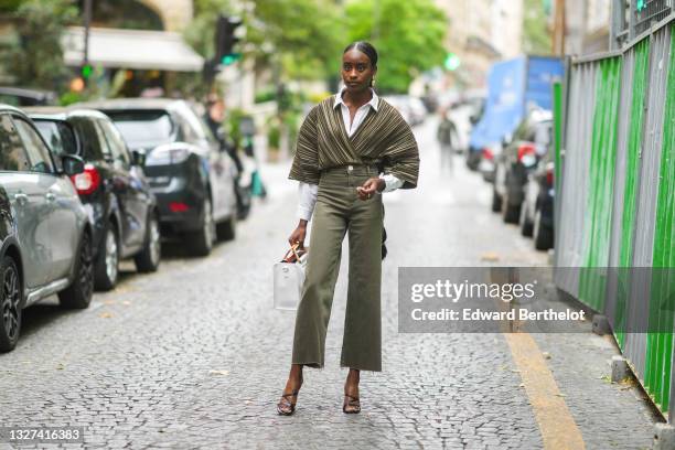 Guest wears gold earrings, a white shirt, a pale green and dark green striped ruffled jacket, khaki denim jeans ripped flared pants, a white matte...