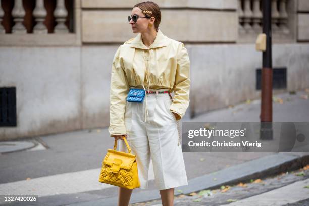 Guest is seen wearing blue Chanel mirco bag, yellow Roger Vivier bag, yellow blouse, white outside Chanel on July 06, 2021 in Paris, France.