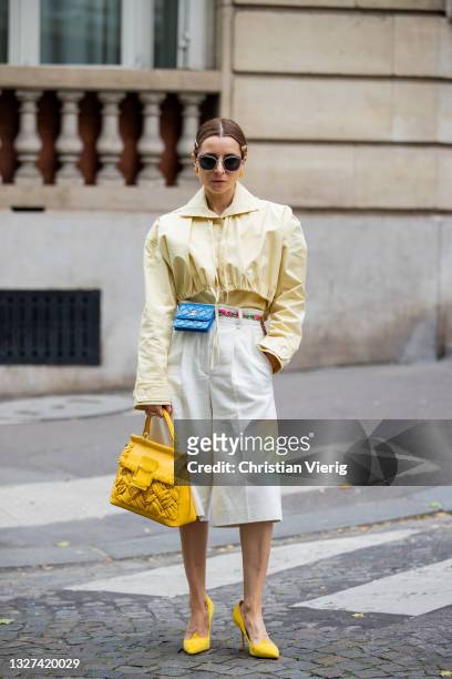 Guest is seen wearing blue Chanel mirco bag, yellow Roger Vivier bag, yellow blouse, white outside Chanel on July 06, 2021 in Paris, France.