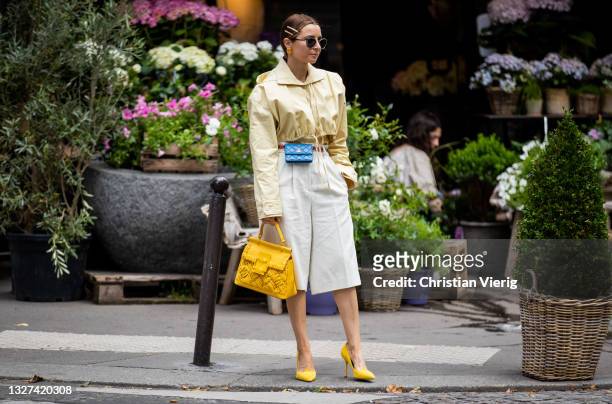 Guest is seen wearing blue Chanel mirco bag, yellow Roger Vivier bag, yellow blouse, white outside Chanel on July 06, 2021 in Paris, France.