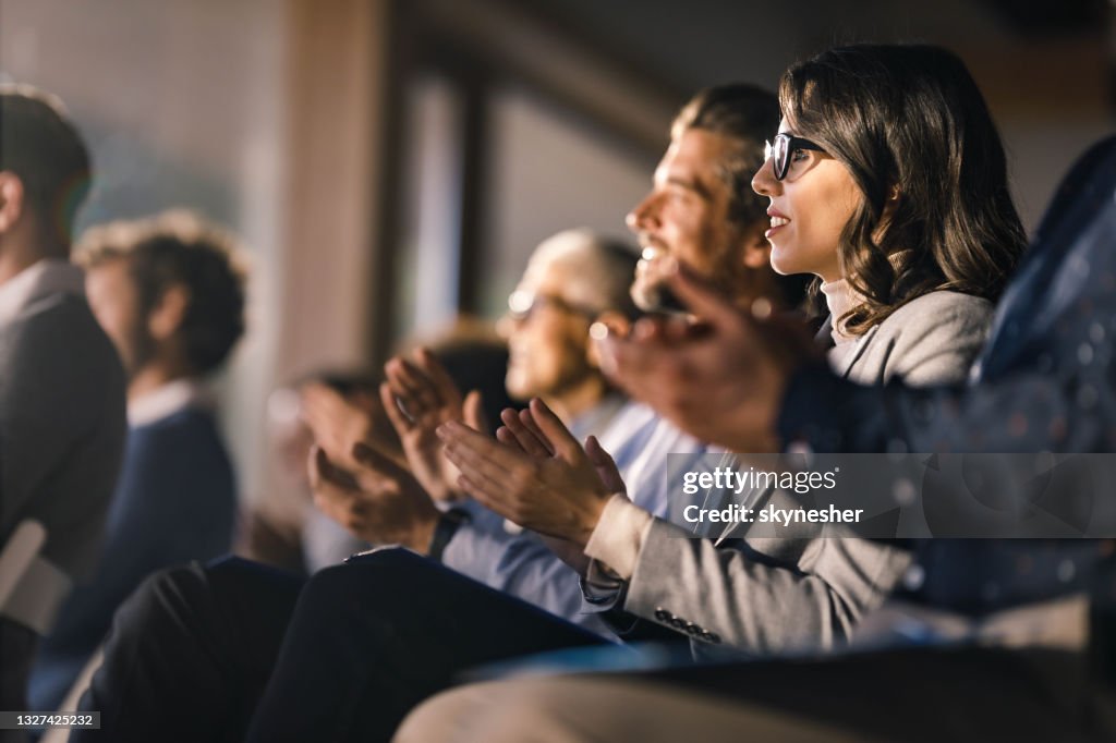 Happy businesswoman and her colleagues applauding on an education event in board room.