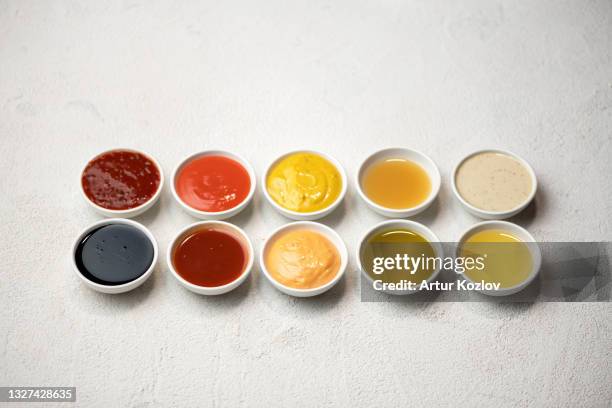 big set of colored sauces in crockery. different sauces, mayonnaise, mustard, soy sauce, oil and ketchup on white background. top side view. tasty food. kitchen utensils - condimento fotografías e imágenes de stock