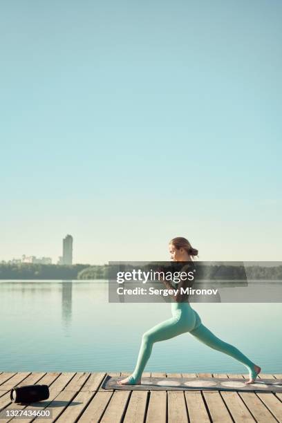 woman practicing yoga near city river. outdoor training concept - emerald city stock pictures, royalty-free photos & images