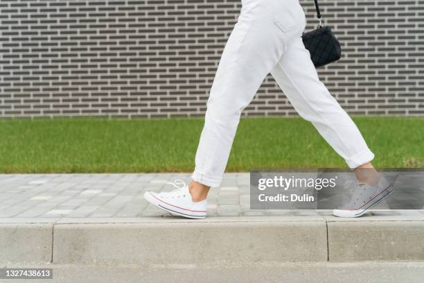 woman's legs in white trousers walking past a brick wall - white pants stock pictures, royalty-free photos & images