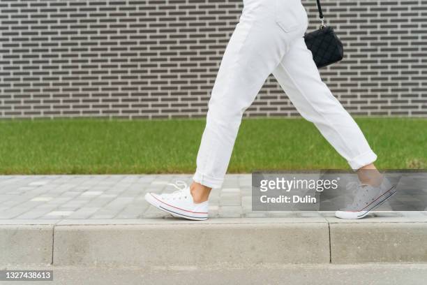 woman's legs in white trousers walking past a brick wall - white pants bildbanksfoton och bilder