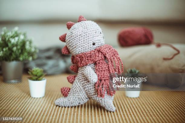 close-up of a crochet dinosaur toy on a table with pot plants - かぎ針編み ストックフォトと画像