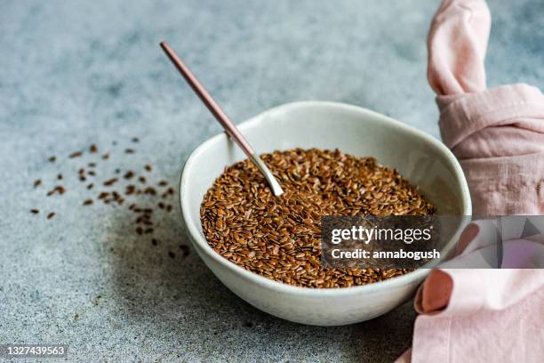 bowl of flax seeds on a table next to a pink napkin - semilla-de-lino fotografías e imágenes de stock