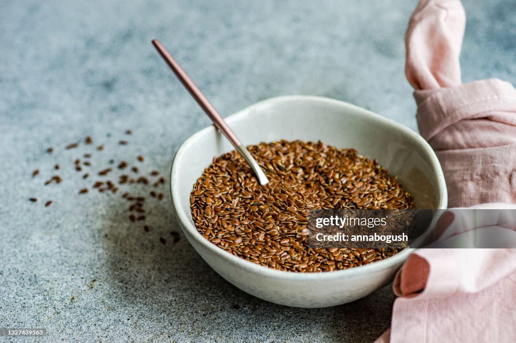 Bowl of flax seeds on a table next to a pink napkin