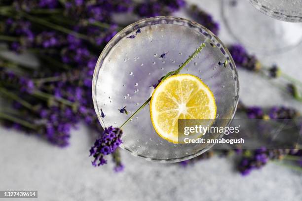 overhead view of a gin and tonic with lemon and lavender flowers on a table - cocktail gin stock-fotos und bilder