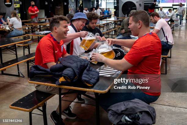 Group of England fans pouring pitchers of beer at Boxpark Wembley on July 07, 2021 in London, England. England has reached the semi-finals of the...