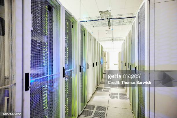 wide shot down rows of server racks in data center - data centre stock pictures, royalty-free photos & images