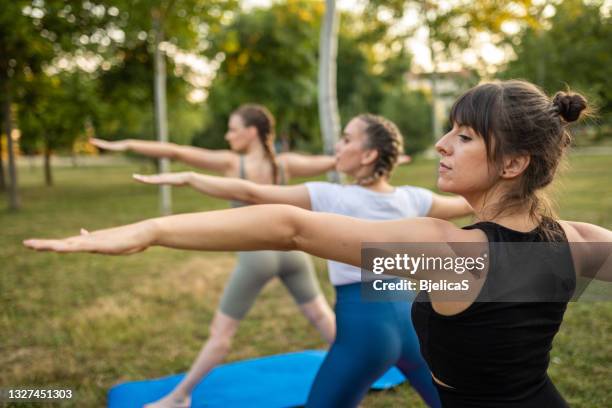 young women on yoga class at public park - bikram yoga stock pictures, royalty-free photos & images