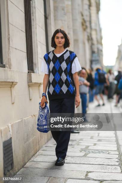 Model wears a white t-shirt, a black / blue and pale gray checkered jacquard print pattern sleeveless pullover, black pants, a blue and white print...